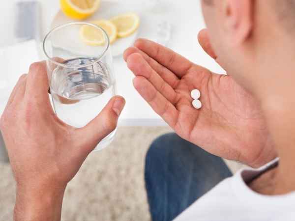 Мужчина держит стакан и таблетки Мужчина держит стакан и таблетки