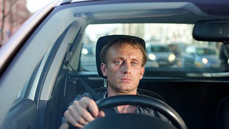 Мужчина сидит в машине за рулем